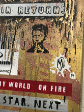 A close-up of a distressed, graffiti-style poster or wall art panel with layered stickers, paint splatters,  and text fragments