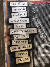 A close-up of a distressed art Painting featuring a vertical writing reading, 'RELIGION IS FOR PEOPLE WHO FEAR HELL,SPIRITUALITY IS FOR PEOPLE WHO HAVE BEEN THERE.' The background is dark and textured with black, white, and gray distressed patterns. This is one of my favorite quotes of David Bowie.