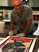 Marco signs a large art print of JIMI HENDRIX on a table for a new client. The print features a black and white graphic of a cat with red and orange accents and the text Power To The People.