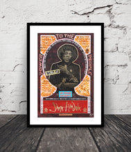 A framed Jimi Handrix framed print  is displayed against a white brick wall on a dark wooden floor. The poster features a black-framed central portrait of Jimi Handrix, surrounded by orange floral corner details and a red bottom section with a signature.