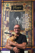 Marco with he's assistant Charlie in front of finished Prince Painting a large, highly detailed, vintage-style collage poster featuring Prince. The poster has gold, purple, and black tones with various text elements and graphic details.