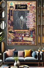 A large framed Prince wall art painting hangs above a blue-gray sofa in a modern living room. The painting features a collage-style design with the word 'Prince' at the top, a black-and-white portrait, piano keys, and many decorative text and graphic elements.